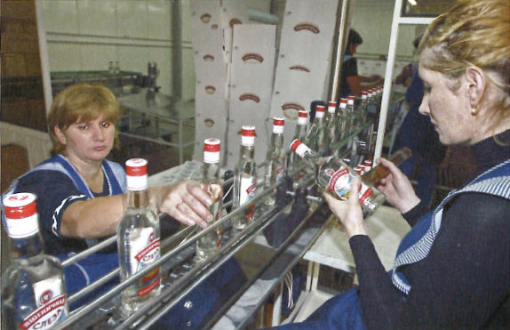 瓶詰されたウォッカにラベルを貼る女性従業員